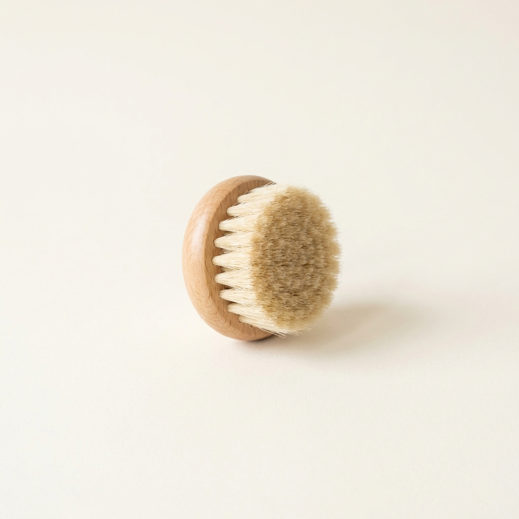Brosse lymphatique visage en bois clair à poils naturels, sur fond crème